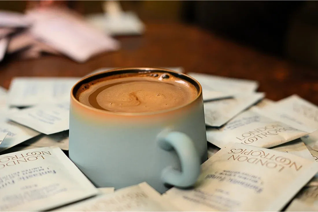 A cup of London Nootropics adaptogenic coffee surrounded by sachets